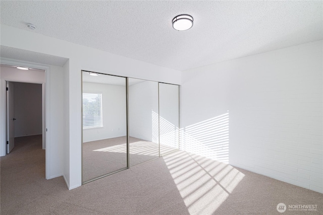 unfurnished bedroom featuring carpet floors, a textured ceiling, and a closet