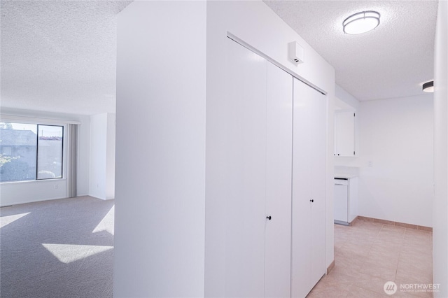 hall with a textured ceiling and baseboards