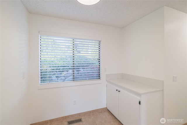 unfurnished dining area featuring a textured ceiling and light tile patterned flooring