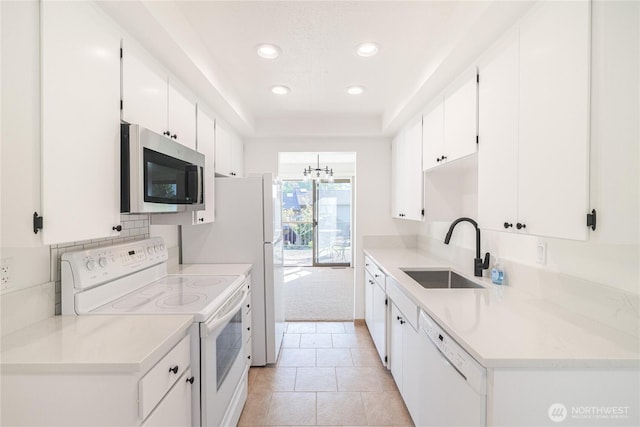 kitchen featuring white appliances, a sink, light tile patterned floors, white cabinets, and recessed lighting