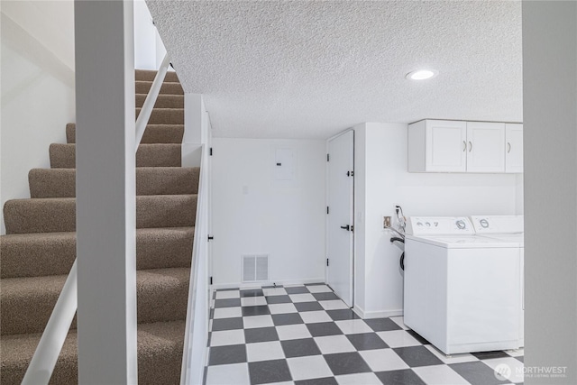 clothes washing area with dark flooring, cabinet space, a textured ceiling, baseboards, and separate washer and dryer