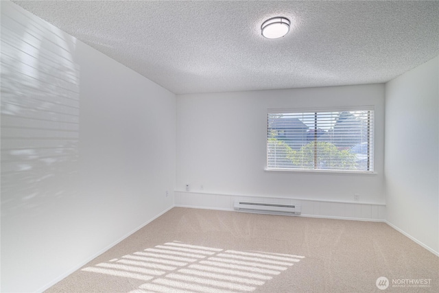 carpeted empty room with a baseboard radiator, a textured ceiling, and baseboards