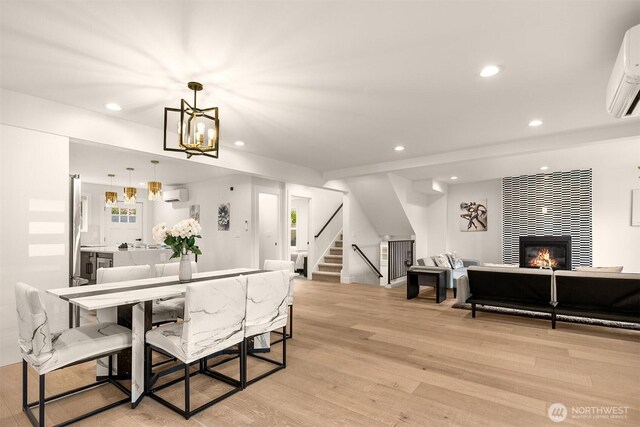 dining space featuring a wall mounted air conditioner, stairway, recessed lighting, light wood-style flooring, and a fireplace