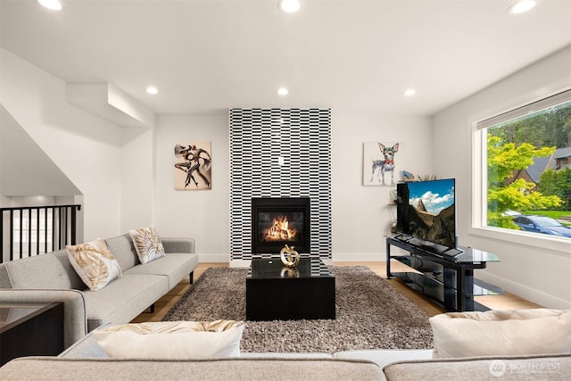 living area with recessed lighting, wood finished floors, a tiled fireplace, and baseboards