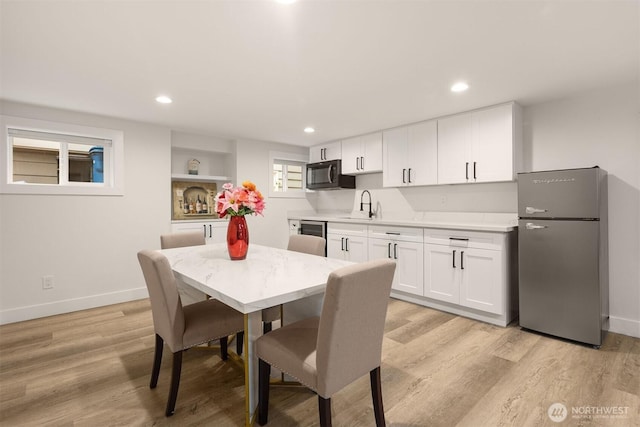dining room featuring baseboards, light wood finished floors, and recessed lighting