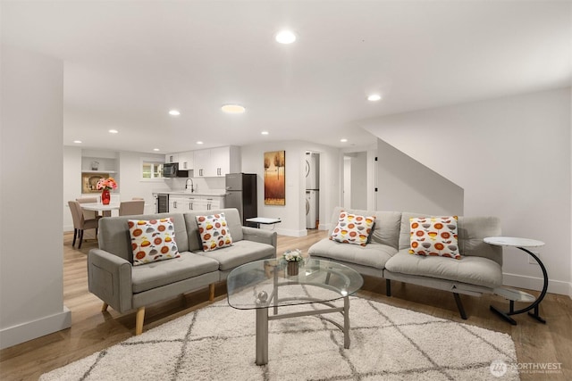living area featuring baseboards, light wood-type flooring, washer / dryer, and recessed lighting