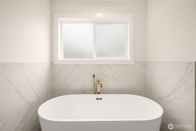bathroom featuring tile walls, a soaking tub, and wainscoting