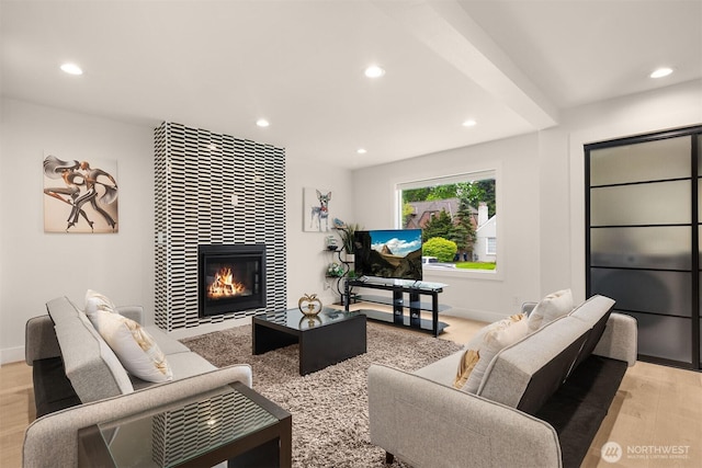 living room with recessed lighting, light wood-style floors, a tiled fireplace, and baseboards