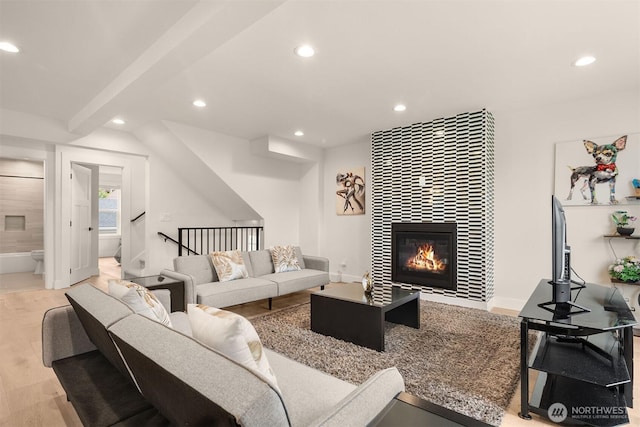 living area featuring recessed lighting, a tile fireplace, wood finished floors, stairway, and baseboards