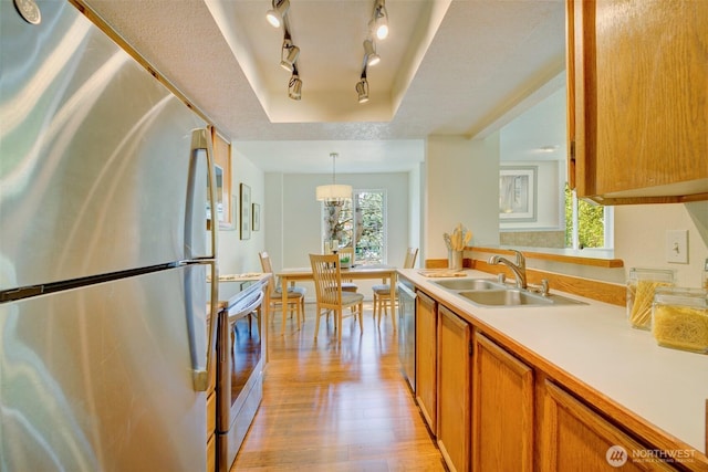5901 Phinney Ave N Unit 103, Seattle, WA 98103 - kitchen with stainless steel appliances, light wood-style floors, light countertops, brown cabinetry, and a raised ceiling