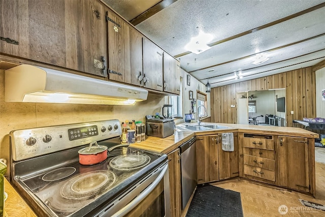 510 Duterrow Rd SE Unit 37, Olympia, WA 98513 - kitchen with stainless steel appliances, under cabinet range hood, a peninsula, a sink, and wooden walls