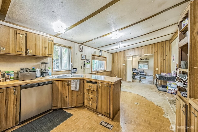 510 Duterrow Rd SE Unit 37, Olympia, WA 98513 - kitchen featuring dishwasher, a peninsula, a sink, wooden walls, and brown cabinetry