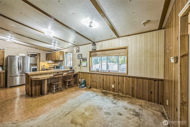 510 Duterrow Rd SE Unit 37, Olympia, WA 98513 - kitchen with freestanding refrigerator, wood walls, a peninsula, a breakfast bar, and a textured ceiling