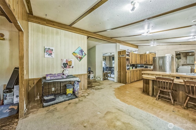 510 Duterrow Rd SE Unit 37, Olympia, WA 98513 - kitchen featuring freestanding refrigerator, brown cabinets, wood walls, washer / dryer, and a kitchen bar