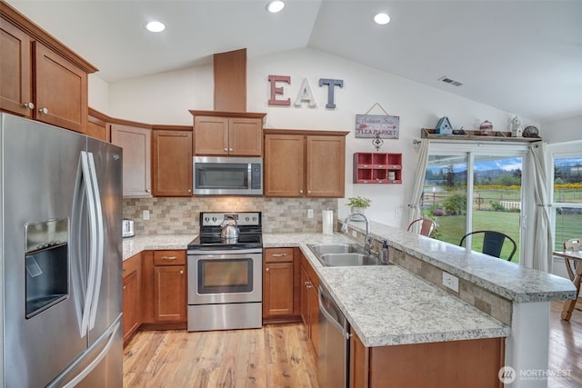 48 Bennett Ln, Oakville, WA 98568 - kitchen featuring stainless steel appliances, a sink, vaulted ceiling, a peninsula, and brown cabinetry