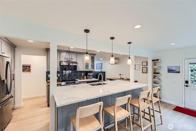kitchen featuring stainless steel fridge, a sink, light wood-type flooring, recessed lighting, and under cabinet range hood
