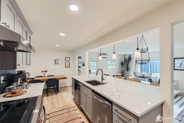 kitchen with stainless steel appliances, a sink, gray cabinets, light wood finished floors, and recessed lighting