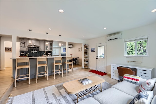 living area featuring a wall mounted AC, light wood finished floors, recessed lighting, and baseboards