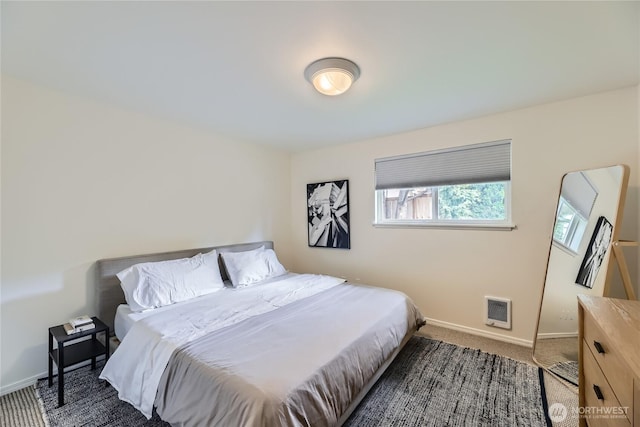 bedroom featuring dark carpet, heating unit, and baseboards
