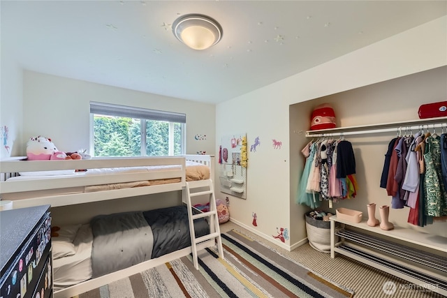 carpeted bedroom featuring baseboards and a closet
