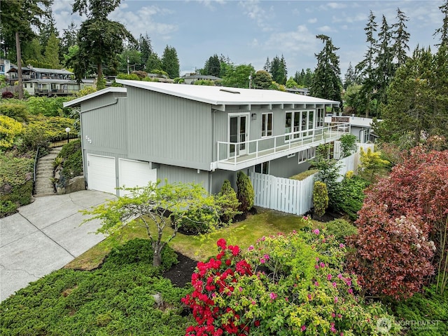 900 Sea Vista Pl, Edmonds, WA 98020 - view of front facade featuring fence, a garage, concrete driveway, and view of wooded area