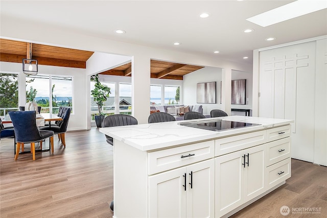 900 Sea Vista Pl, Edmonds, WA 98020 - kitchen featuring black electric cooktop, beam ceiling, wood ceiling, a skylight, and white cabinets
