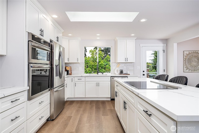 900 Sea Vista Pl, Edmonds, WA 98020 - kitchen with appliances with stainless steel finishes, a skylight, healthy amount of natural light, light wood-style flooring, and recessed lighting