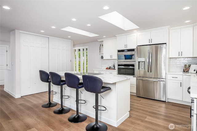 900 Sea Vista Pl, Edmonds, WA 98020 - kitchen featuring appliances with stainless steel finishes, a skylight, recessed lighting, a center island, and white cabinets