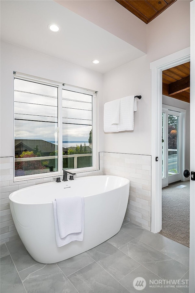 900 Sea Vista Pl, Edmonds, WA 98020 - bathroom featuring plenty of natural light, marble look tiles, a freestanding bath, recessed lighting, and tile walls