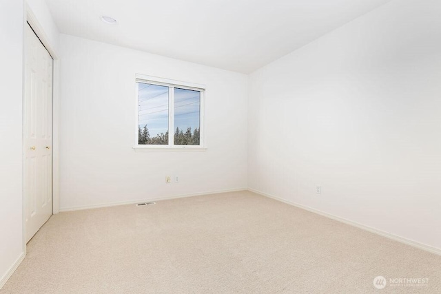 unfurnished bedroom featuring light carpet, a closet, and baseboards