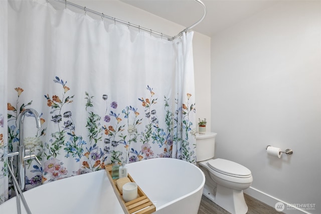 13520 Burn Rd, Arlington, WA 98223 - bathroom featuring baseboards, wood finished floors, a soaking tub, and toilet