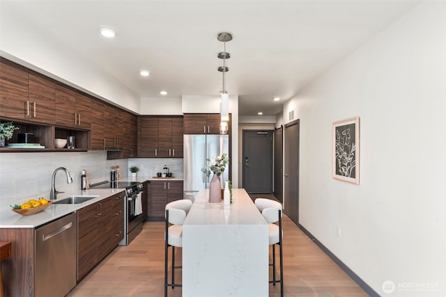 11903 NE 128th St Unit 612, Kirkland, WA 98034 - kitchen with appliances with stainless steel finishes, a sink, a breakfast bar area, light wood-type flooring, and recessed lighting