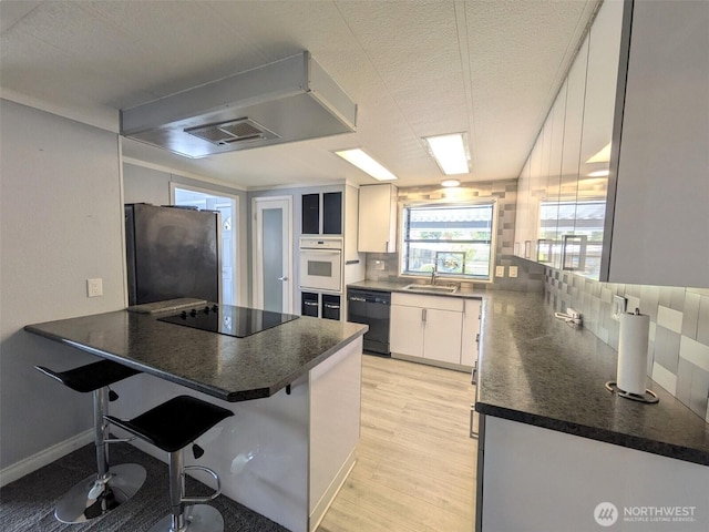 201 Union Ave SE Unit 136, Renton, WA 98059 - kitchen featuring black appliances, a peninsula, a sink, dark countertops, and white cabinets