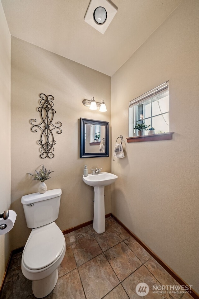 bathroom with toilet, baseboards, and a sink