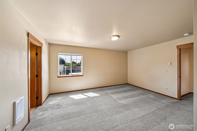 unfurnished room with carpet floors, baseboards, and heating unit