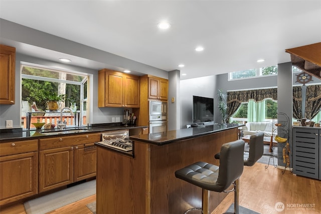 7819 Tolt River Rd NE, Carnation, WA 98014 - kitchen featuring a sink, recessed lighting, light wood-style floors, brown cabinets, and stainless steel microwave