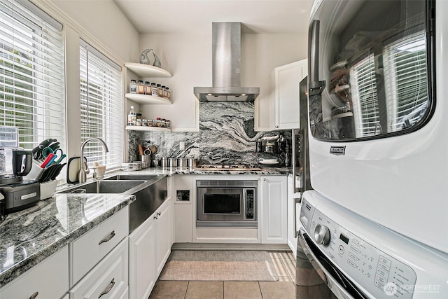 4316 Crystal Lane Loop SE, Puyallup, WA 98372 - kitchen with stacked washer / dryer, wall chimney exhaust hood, a sink, stone countertops, and white cabinets