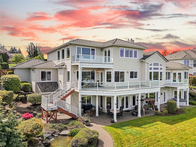 4316 Crystal Lane Loop SE, Puyallup, WA 98372 - back of property at dusk with a balcony, a lawn, a chimney, and a patio area