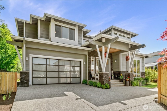 view of front facade with stone siding, concrete driveway, a garage, and fence