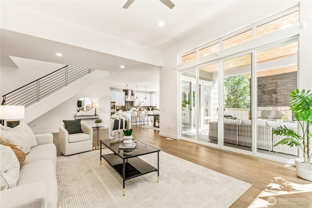 living area featuring stairway, a ceiling fan, light wood-style flooring, recessed lighting, and baseboards