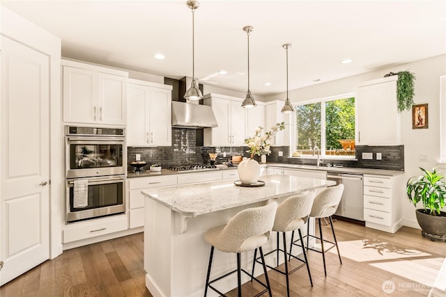 kitchen with stainless steel appliances, a breakfast bar, decorative backsplash, light wood finished floors, and recessed lighting