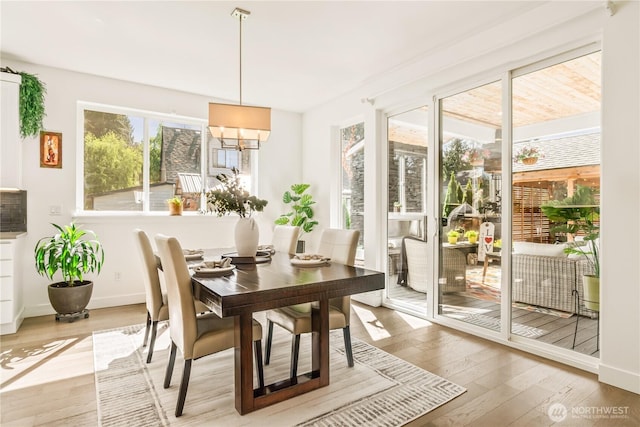 dining space with light wood finished floors, baseboards, and a chandelier