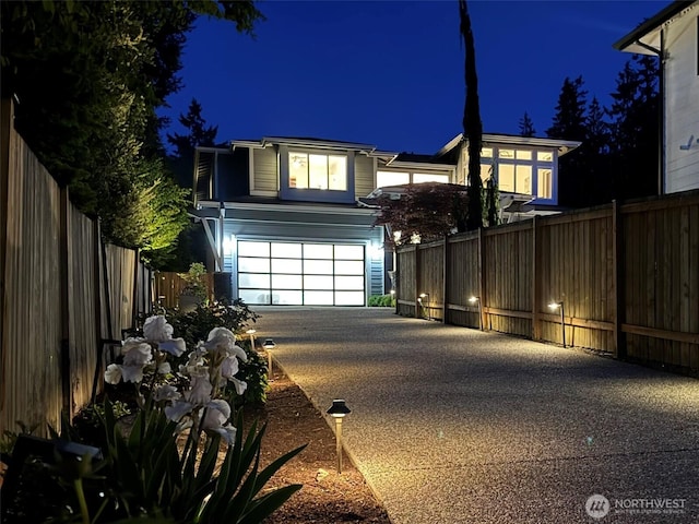 view of front facade with driveway, a garage, and fence