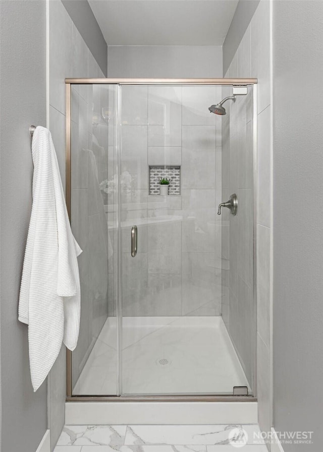 full bath with marble look tile flooring and a stall shower