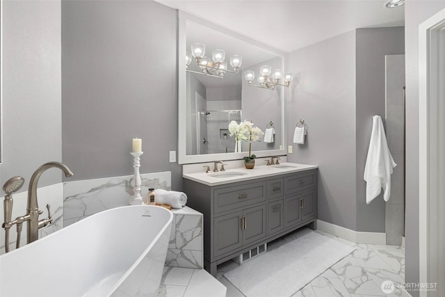 full bath with marble finish flooring, a soaking tub, double vanity, and a chandelier