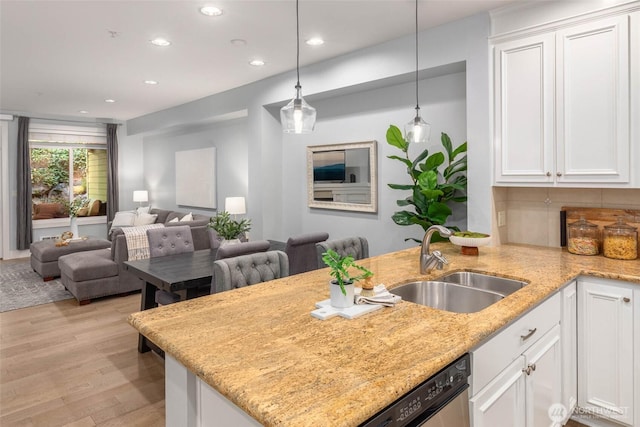 kitchen with a sink, white cabinets, light wood finished floors, a peninsula, and pendant lighting
