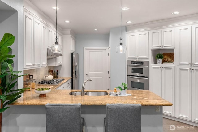 kitchen with a sink, appliances with stainless steel finishes, a peninsula, white cabinetry, and recessed lighting