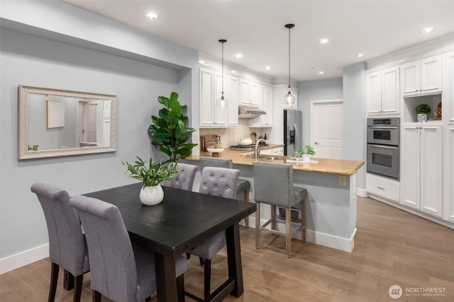 dining room with light wood finished floors, baseboards, and recessed lighting