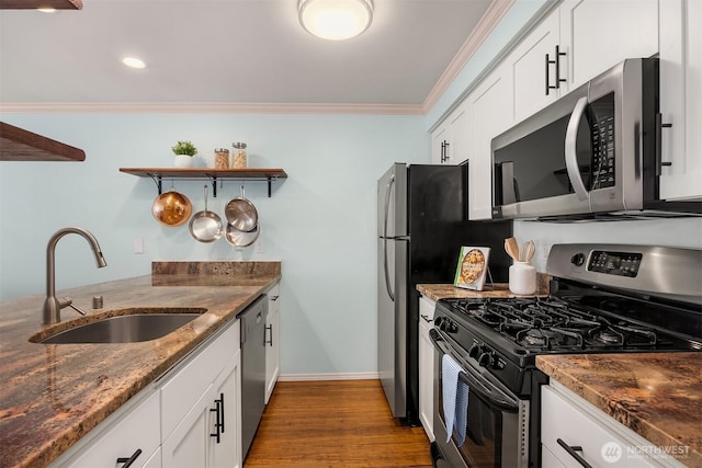 kitchen with stainless steel appliances, a sink, ornamental molding, open shelves, and dark stone counters