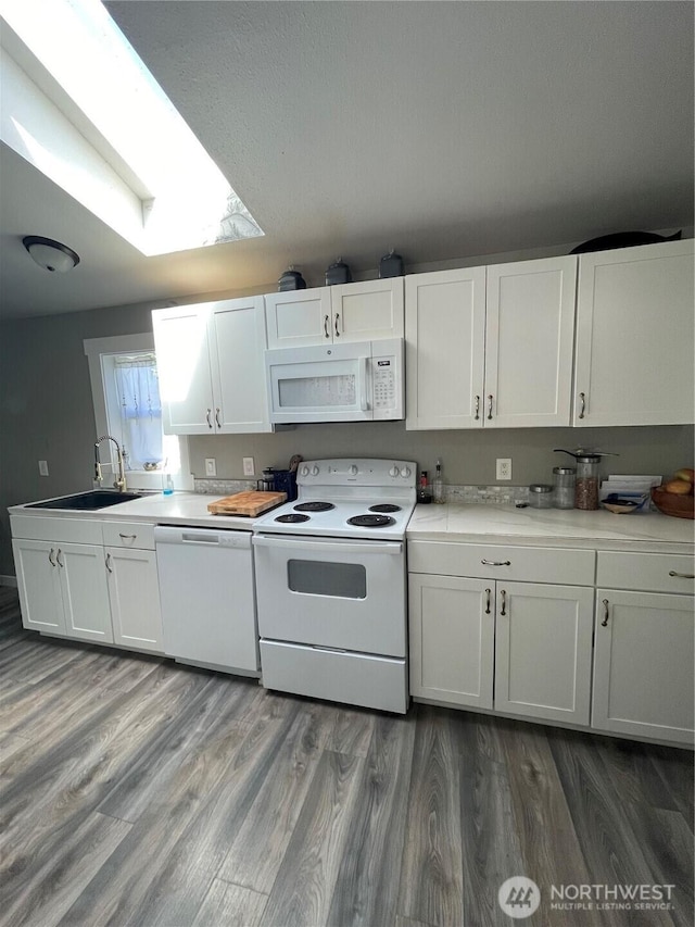 5600 Mt Solo Rd Unit 114, Longview, WA 98632 - kitchen with white appliances, a skylight, white cabinets, wood finished floors, and light countertops